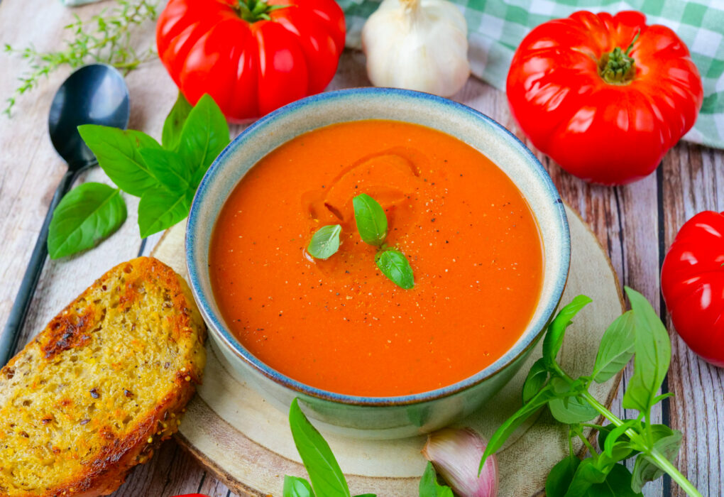 Roasted Tomato and Garlic Soup in a white bowl with fresh basil
