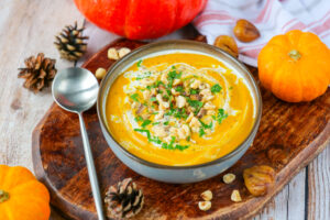 Creamy pumpkin and chestnut soup in a bowl with parsley and hazelnuts